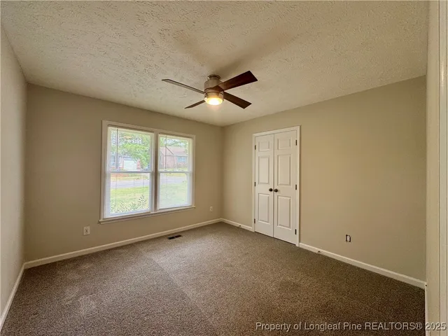 an empty room with chandelier fan and windows