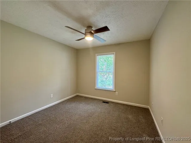 an empty room with a ceiling fan and window