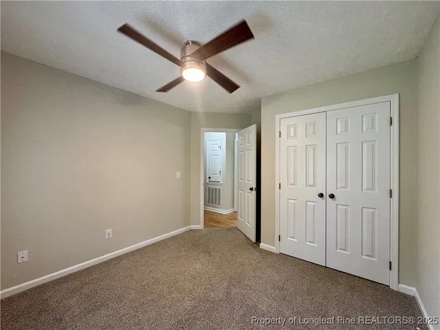 an empty room with staircase and ceiling fan