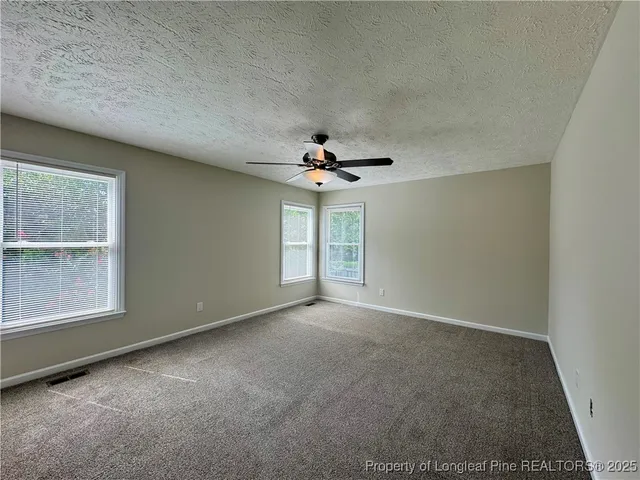 an empty room with a window and a ceiling fan