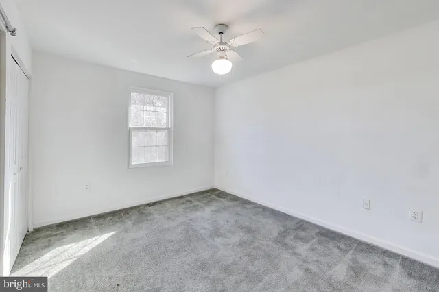 an empty room with windows and ceiling fan