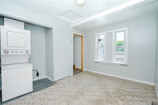 a view of an empty room with closet and a window