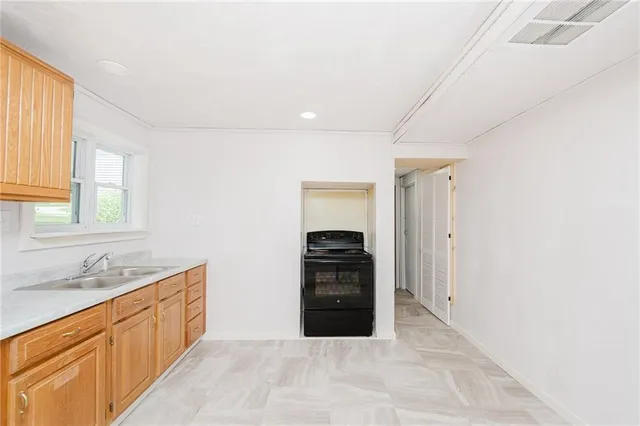 a large white kitchen with a sink and dishwasher a stove top oven with wooden floor