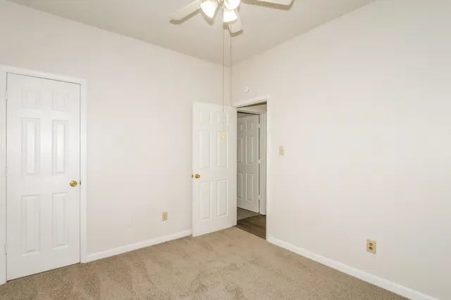 a view of an empty room with a chandelier fan