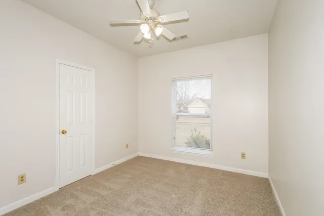 an empty room with a window and a fan