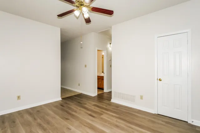 an empty room with wooden floor and a ceiling fan