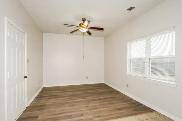 a view of empty room with wooden floor and fan