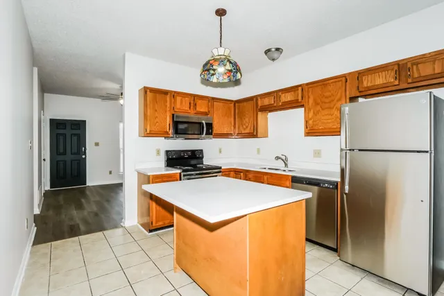 a kitchen with stainless steel appliances granite countertop a refrigerator a stove and a sink
