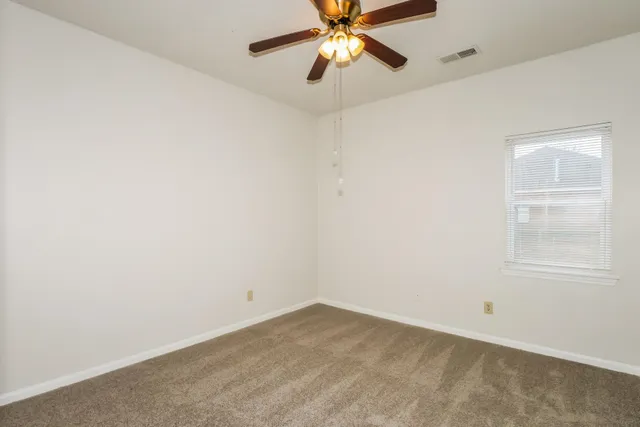 an empty room with chandelier fan and window
