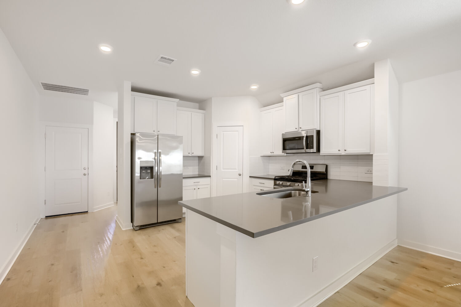 356 Brandywine Road Hutto, TX 78634 - Photo 5 of 11 A contemporary kitchen space boasts gleaming stainless steel appliances and abundant white cabinetry, seamlessly integrating a central island with a sink.