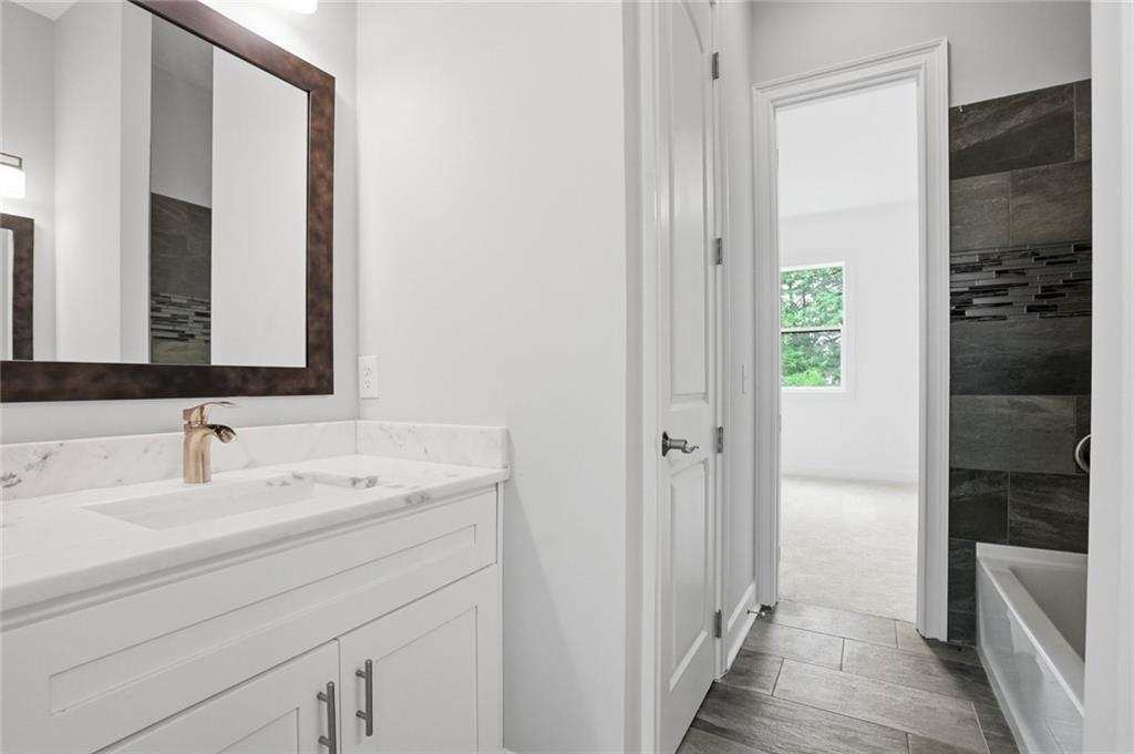 2415 West Rugby Avenue Atlanta, GA 30337 - Photo 34 of 40 a en suite bathroom with a sink a mirror and a shower