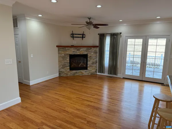 an empty room with wooden floor fireplace and windows