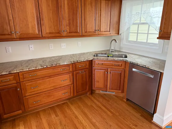 a kitchen with granite countertop wooden cabinets a sink and dishwasher