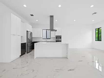 a large white kitchen with a sink a counter top space and stainless steel appliances