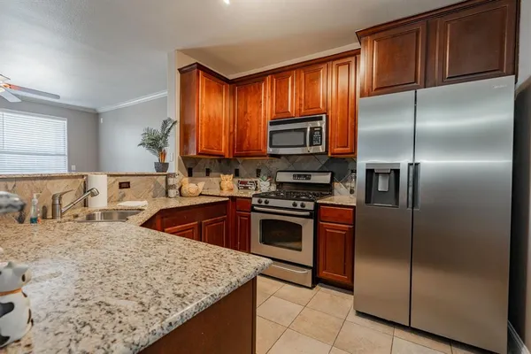 a kitchen with stainless steel appliances granite countertop a refrigerator a stove a sink and a microwave