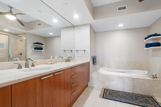 a bathroom with a double vanity sink mirror and bathtub