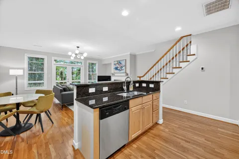 a kitchen with stainless steel appliances granite countertop a stove and a view of living room