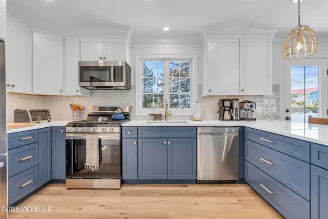 a kitchen with stainless steel appliances granite countertop a stove a sink dishwasher a refrigerator and a microwave oven with wooden floor