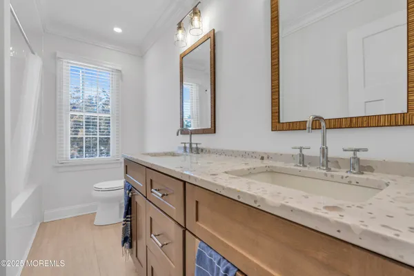 a bathroom with a granite countertop sink a toilet a mirror and a window