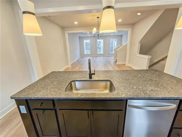 a kitchen with kitchen island granite countertop a sink a counter space appliances and cabinets