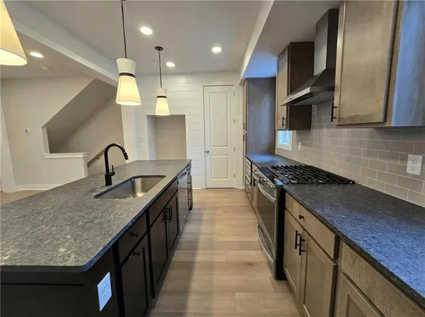 a kitchen with kitchen island granite countertop a stove a sink a counter space and a window