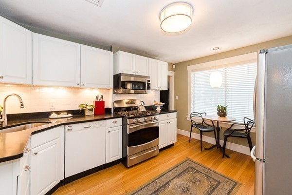52 Aberdeen Road Arlington, MA 02476 - Photo 16 of 30 a kitchen with granite countertop a stove a sink and white cabinets with wooden floors