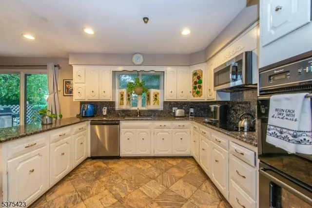 a large kitchen with stainless steel appliances granite countertop a stove and cabinets