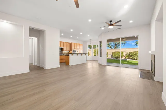 a view of an empty room with kitchen appliances and wooden floor