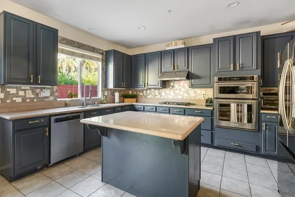 a kitchen with kitchen island granite countertop a sink counter top space appliances and cabinets