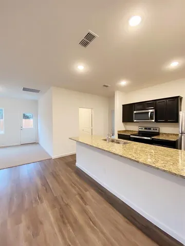 a view of kitchen with stainless steel appliances granite countertop a stove a sink and a refrigerator