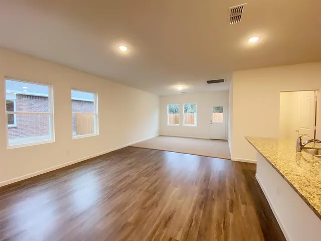 a view of kitchen with kitchen island granite countertop a stove and a sink