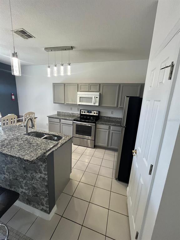 435 Kettering Road Davenport, FL 33897 - Photo 7 of 8 a kitchen with stainless steel appliances granite countertop a sink stove and refrigerator