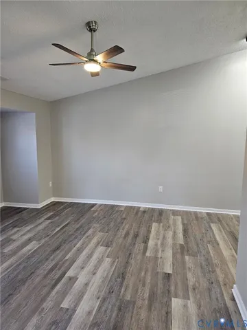 an empty room with wooden floor and chandelier fan