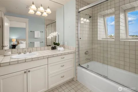 a bathroom with a sink a large mirror and a bathtub with shower