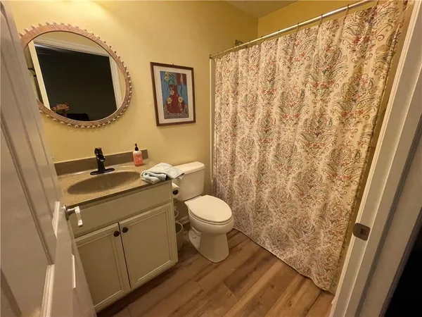 a bathroom with a granite countertop sink toilet a mirror and shower curtain