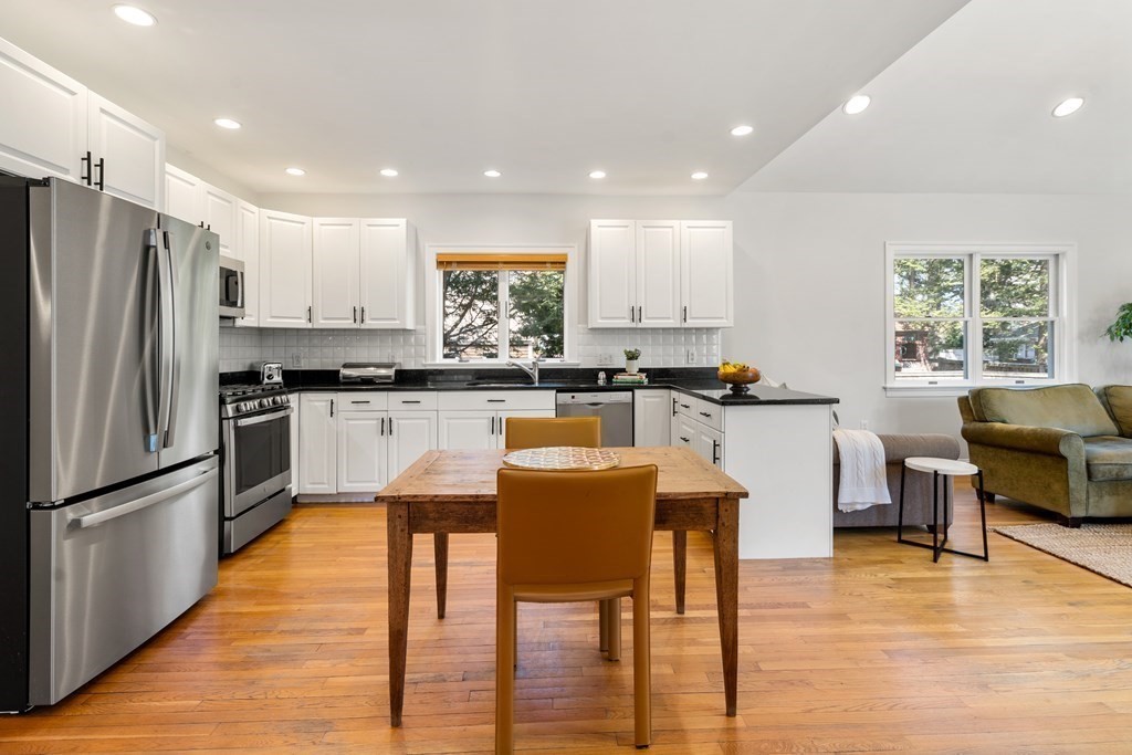 19 Elmore Street Newton, MA 02459 - Photo 8 of 40 a kitchen with stainless steel appliances granite countertop a refrigerator a stove top oven and a dining table with wooden floor