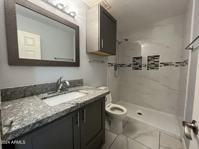 a bathroom with a granite countertop sink a mirror and a bathtub
