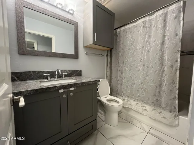 a bathroom with a granite countertop sink toilet and shower