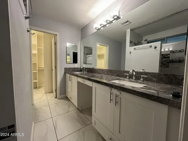 a spacious bathroom with a granite countertop sink a mirror and a shower