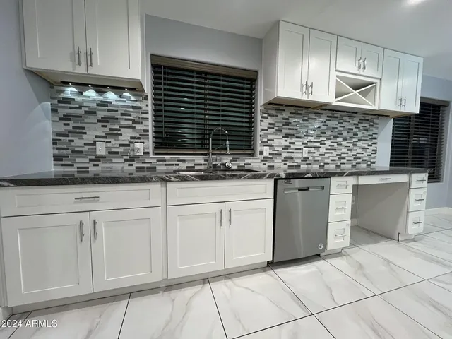 a kitchen with granite countertop white cabinets and sink