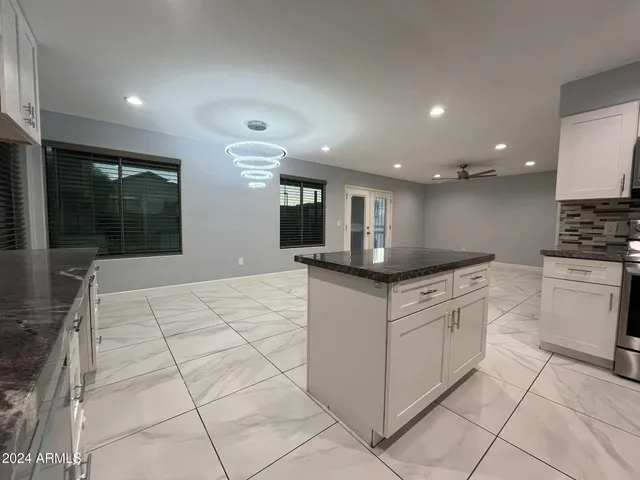 a kitchen with stainless steel appliances kitchen island granite countertop a refrigerator and a stove top oven