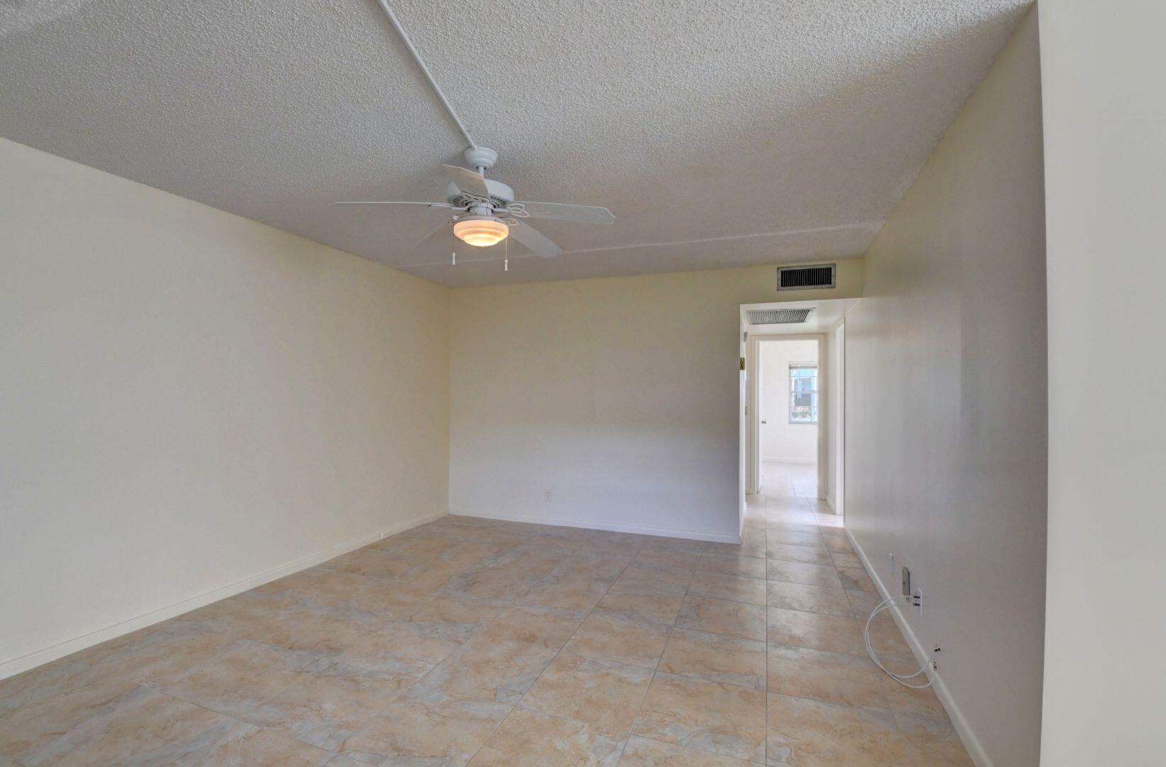 46 Brighton B Boca Raton, FL 33434 - Photo 12 of 50 an empty room with a ceiling fan and carpet