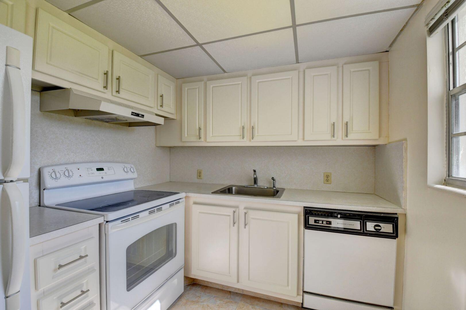 46 Brighton B Boca Raton, FL 33434 - Photo 5 of 50 a kitchen with stainless steel appliances granite countertop a sink a stove and cabinets