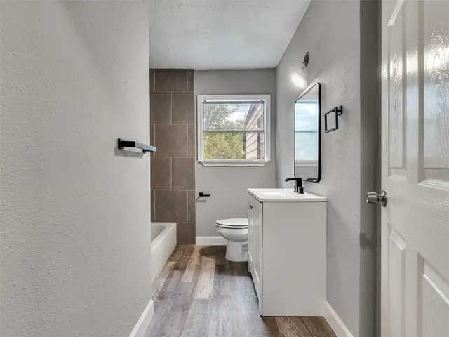 a bathroom with a granite countertop toilet a sink and a mirror