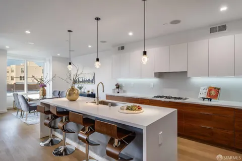 a kitchen with kitchen island a stove a table and chairs in it