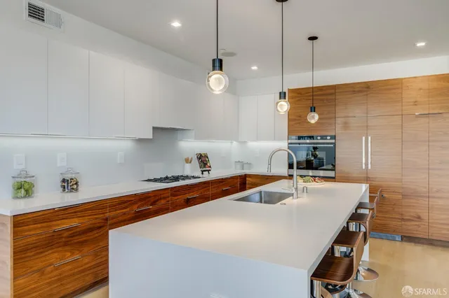 a kitchen with stainless steel appliances granite countertop a sink a stove and a wooden floors