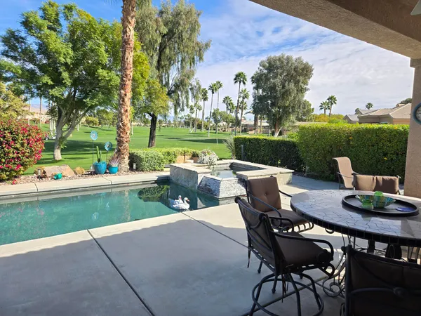 a view of a patio with table and chairs potted plants and a palm tree