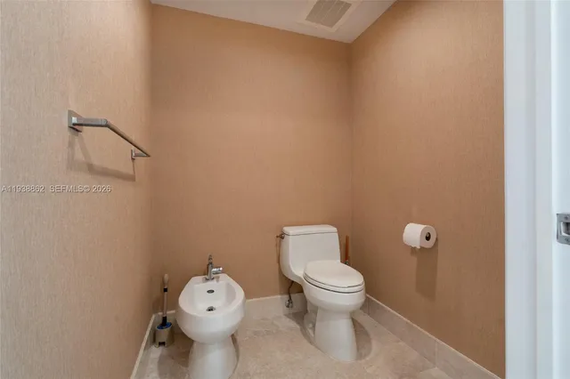 a white toilet sitting next to a white sink and vanity