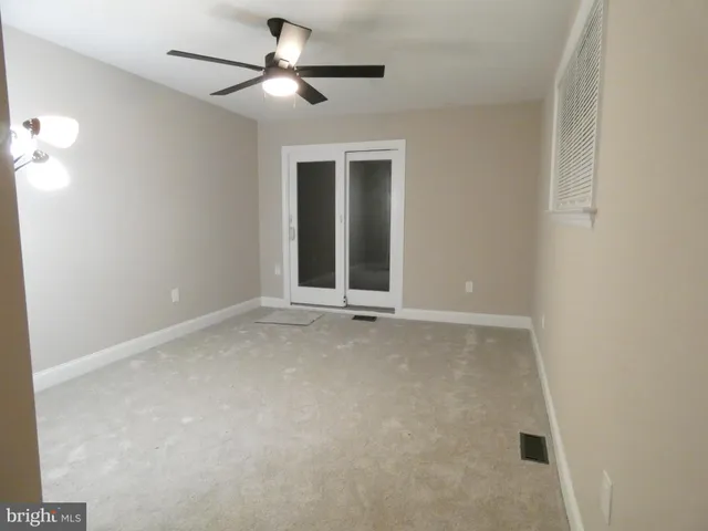 an empty room with a ceiling fan and a window