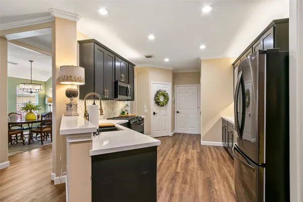 a kitchen with stainless steel appliances a refrigerator a sink dishwasher and wooden cabinets with wooden floor